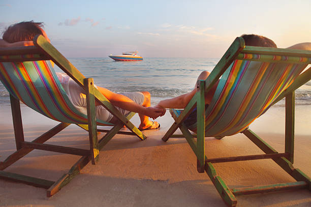 istock Happy couple sitting at sun chairs on the beach 544970820