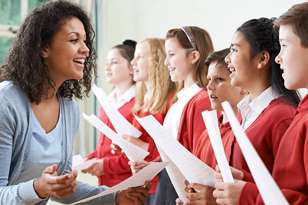 bambini a scuola cori essere incoraggiata da insegnante - singing lesson foto e immagini stock