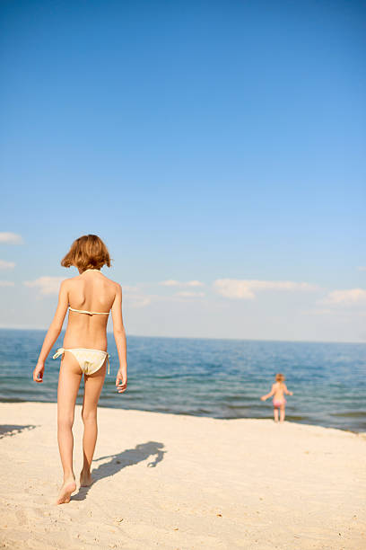 Rear view of girl walking over beach, her shadow reflected on sand