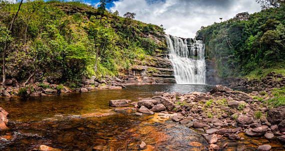 Panoramic view of Sakaika waterfall or Salto Sakaika. La Gran Sabana Venezuela. This beautiful and famous place is located near the main road crossing La Gran Sabana. The savanna, or La Gran Sabana, spreads into the regions of the Guiana Highlands and south-east into Bolívar State all the way to the borders with Brazil and Guyana. The Gran Sabana has an area of 10,820 km2 and is part of the second largest National Park in Venezuela, the Canaima National Park. The largest National Park in Venezuela is Parima Tapirapecó located in the Amazon State. The average temperature is around 20 °C , but at night can drop to 13 °C, nevertheless on top of the tepuis it can reach 0 °C (32 °F). La Gran Sabana shows one of the most unusual landscapes in the world, with rivers, waterfalls, deep and huge valleys, impenetrable jungles and savannahs that host large numbers and varieties of plant and animal species. The most prominent geological features are the table top mountains known as tepuis.