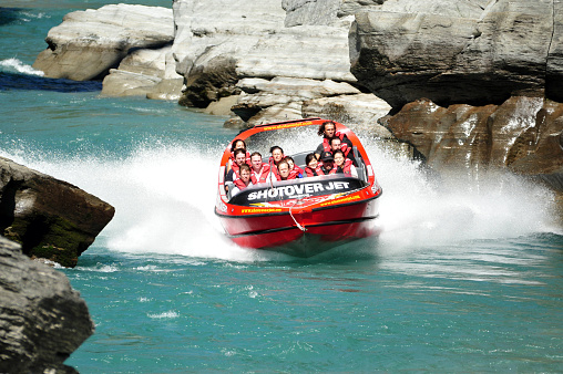 Queenstown, New Zealand - June 28, 2016: Tourists enjoy a high speed jet boat ride on the Shotover River in Queenstown, New Zealand. Queenstown is one of the most popular summer resort in NZ.