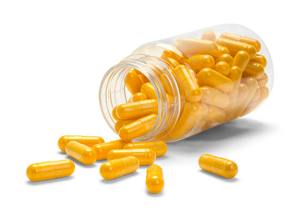 bouteille de pilule orange renversée - herbal medicine vitamin pill capsule nutritional supplement photos et images de collection