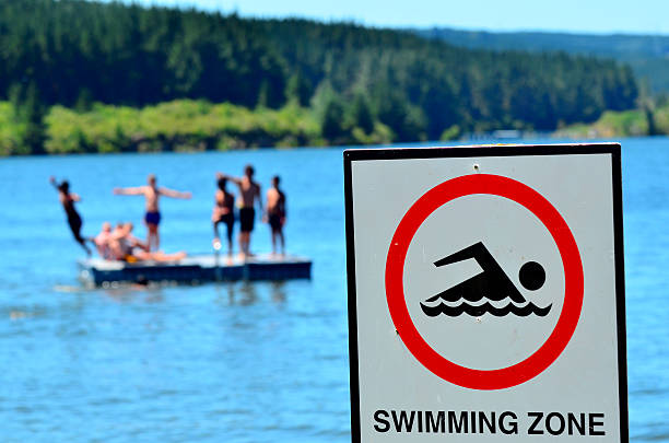 Authorise swimming zone Mangakino, New Zealand - January 15, 2016: Authorise swimming zone sign in front of youth swimming. Drowning ranks 5th among the leading causes of unintentional injury death in the USA. Every day, about 10 people die from unintentional drowning. waikato river stock pictures, royalty-free photos & images
