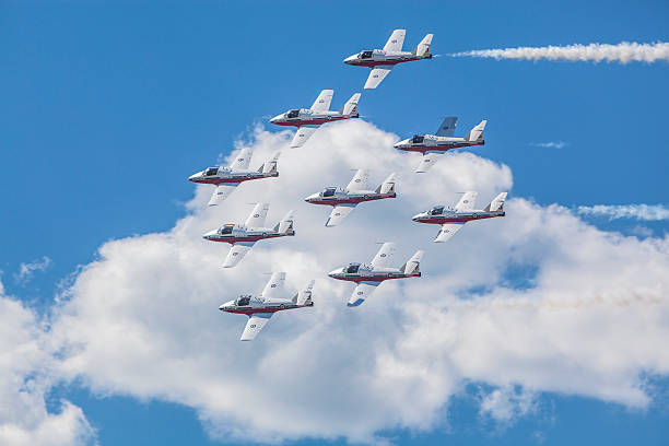 Snowbirds in blue sky and clouds Gatineau, Canada - June 30, 2016: The Wings over Gatineau Airshow is a airshow at the Gatineau Executive Airport. This image shows the Canadian Forces Snowbirds aerial demonstration team flying in the sky. stunt airplane airshow air vehicle stock pictures, royalty-free photos & images
