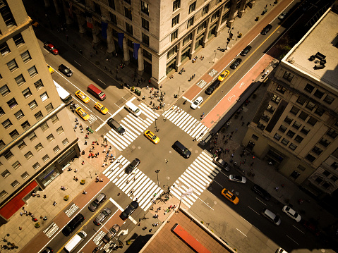 Bird's eye view of Manhattan, looking down at people and yellow taxi cabs going down 5th Avenue.  Toned, Instagram photography with slight vignette.