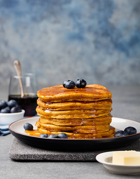 istock Pumpkin pancakes with maple syrup and blueberries on a plate. 544984864