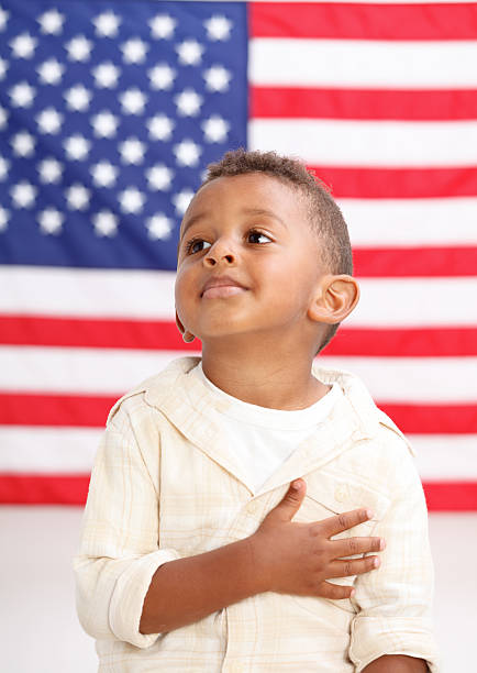 niño frente a la bandera americana con la mano sobre el corazón - child patriotism saluting flag fotografías e imágenes de stock