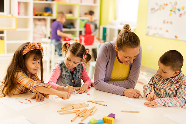 istock Preschool teacher sketching with kids during art class at kindergarten. 544989792