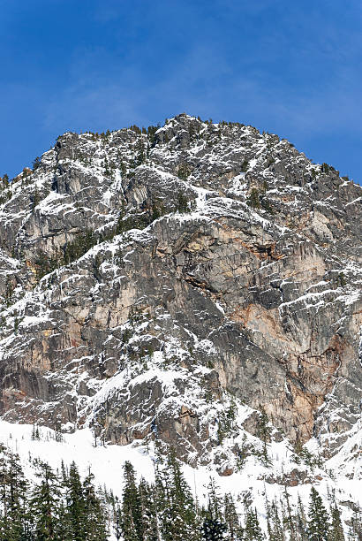 istock Blue Sky Over Tall Rocky Peak Covered in Winter Snow 544991296