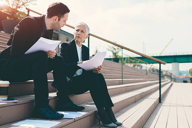 istock Businesspeople Sitting on Stairs And Examining Paperwork. 544992872