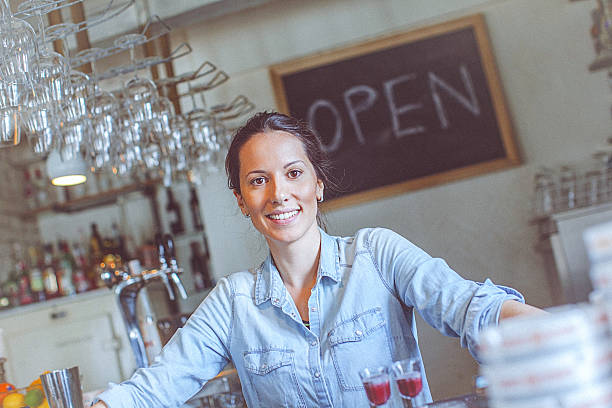 Young happy female bar owner posing at the bar counter stock photo