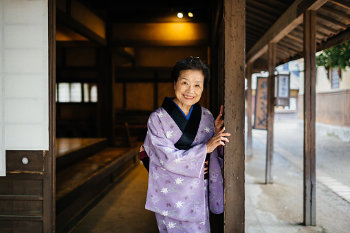 senior japanese woman standing in the door of an old Edo Period Townhouse