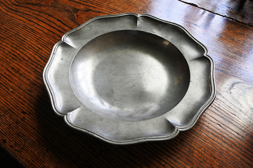 Single pewter plate on a polished wooden surface.