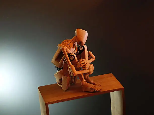 Wooden doll (or armature) hugging its knees