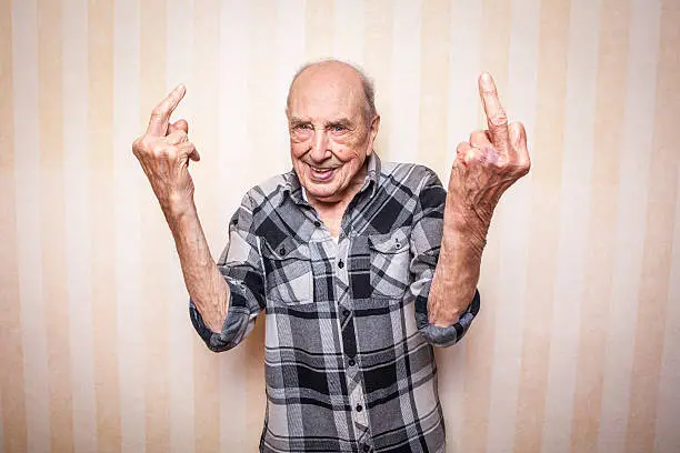 Photo of cool funny elder man making middle finger sign