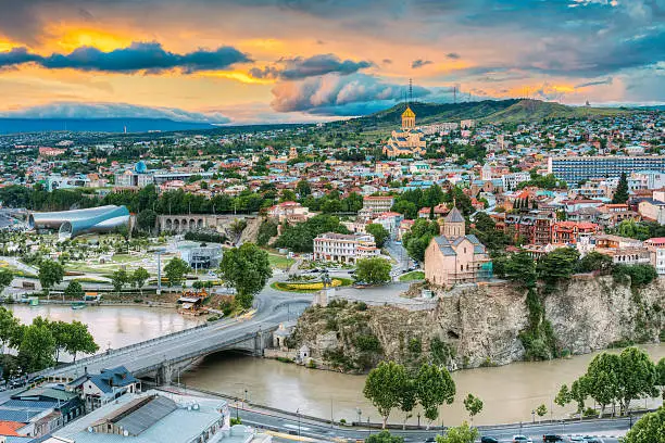 Evening View Of Tbilisi At Colorful Sunset, Georgia. Summer Cityscape. On Photograph Visible A New Concert Hall, Avlabar Residence - Presidential Administration Of Georgia, Holy Trinity Cathedral Of Tbilisi, Metekhi Church