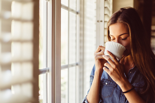 Young woman with coffee cup near the window