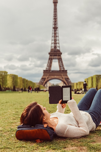 Young girl resting and reading an e-book near the Eiffel tower