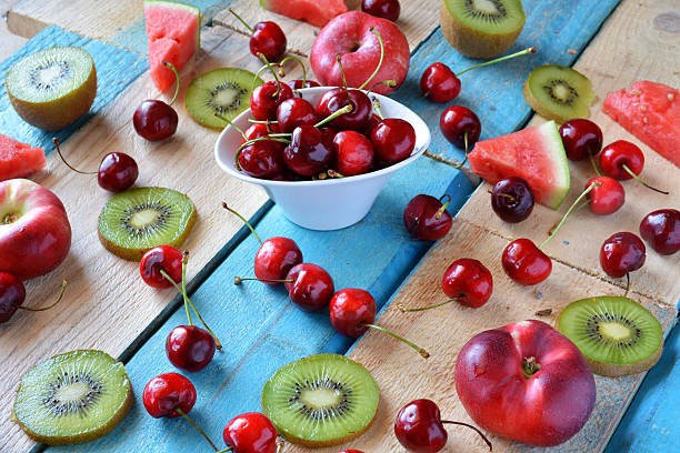 rustic table full of pieces of watermelon, melon, kiwi and cherries