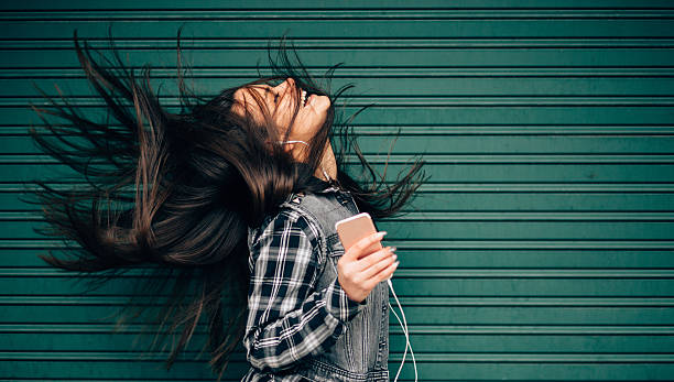 Teenage girl listening to the music and shaking head Young woman tossing hair while enjoying the music throwing photos stock pictures, royalty-free photos & images