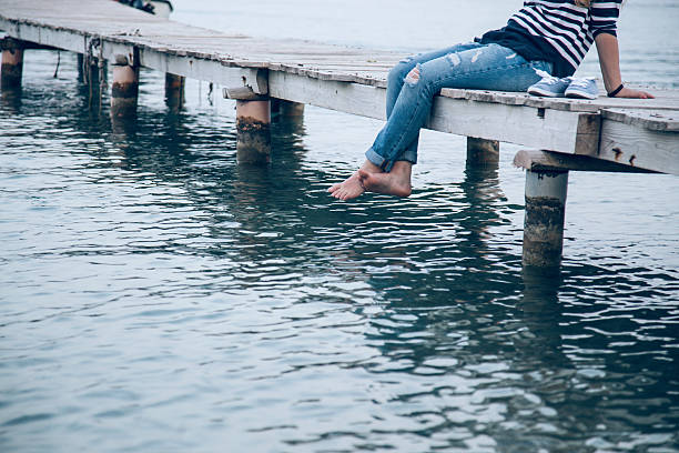 istock Young woman sitting and relaxes on pier 545100482