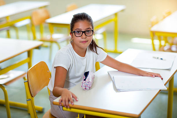 istock Girl with glasses sitting at a table in the classroom 545100640