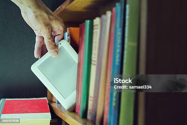 Man Hand Gets Ebook Among Old Books From The Bookshelf Stock Photo - Download Image Now