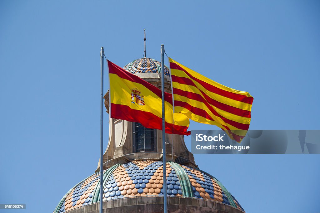 Spanish and Catalan Flag Spanish and Catalan flag flying together against blue sky on a bank building in Barcelona, Spain Catalonia Stock Photo