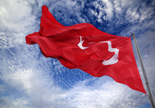 Waving flag of Turkey against blue sky with clouds