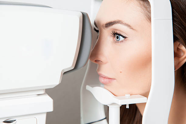 istock brunette looking at eye test machine in ophthalmologist 545111874