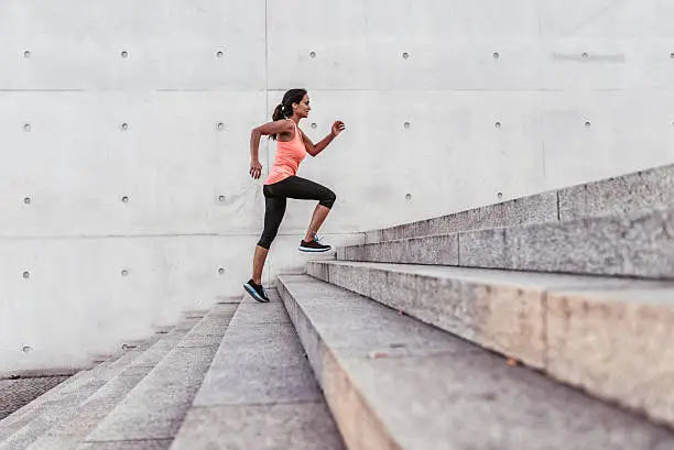 Photo of latina sports woman running up outdoor stairway in berlin