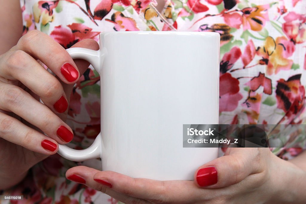 Girl is holding white cup in hands. Girl is holding white cup, mug in hands. Mockup for designs. Adult Stock Photo
