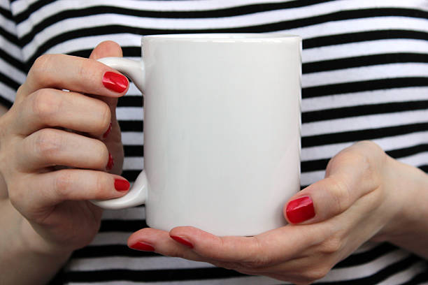 Girl is holding white cup in hands.