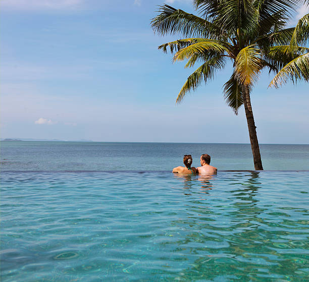 istock Young couple relaxing in infinity pool under coco palms 545118228