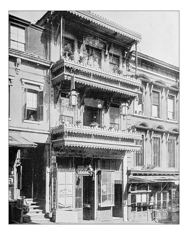 Antique photograph of a traditional house in Chinatown (San Francisco, California, USA) in a 19th century picture. The chinese neighborhood of this city is the oldest Chinatown in North America (established in 1848). This traditionl building houses a company (see the windows)