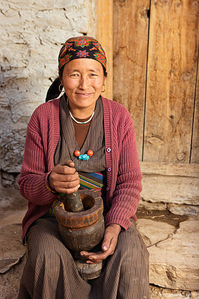istock Tibetan woman using a mortar to make  flour. Mustang, Nepal 545120532