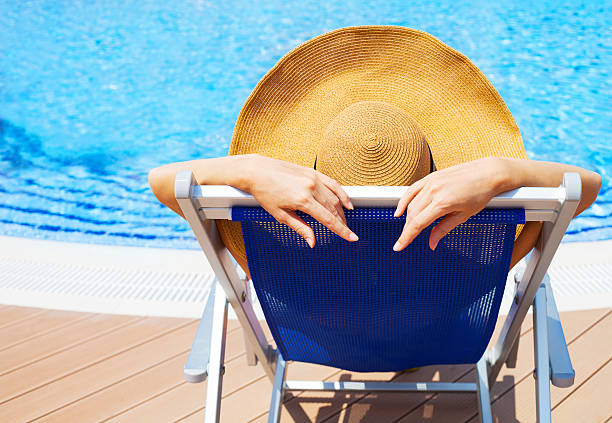 istock Young woman lying on deckchair by swimming pool 545124012