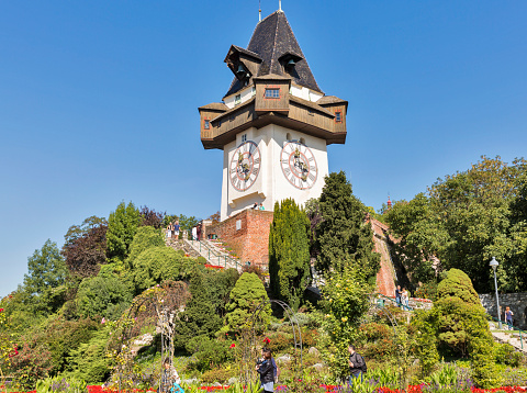 Graz, Austria - September 12, 2015: Unrecognized people walk in Schlossberg garden in front of old clock tower Uhrturm.