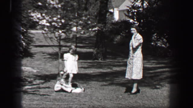 1939: Mother calling young girls in white formal sundress to come inside for supper.