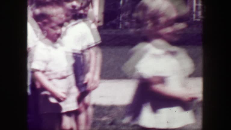 1949: School children closeup running woman teachers flower print dress.