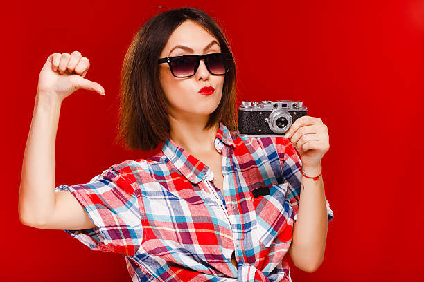 istock Cheerful young woman holding retro camera in her hand 545239738