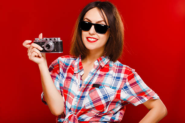 istock Smiling girl holding retro camera on red background 545239862
