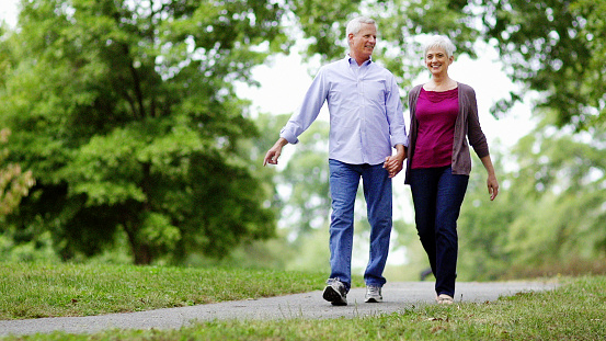 Rear view of a senior couple going for a relaxing walk in the park holding hands