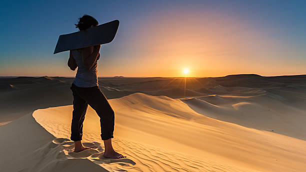 mujer joven sandboard en el desierto del sahara durante la puesta del sol, áfrica - great sand sea fotografías e imágenes de stock