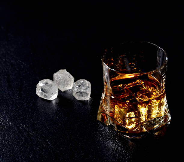 istock Whiskey with ice in glass isolated on black background 545242618