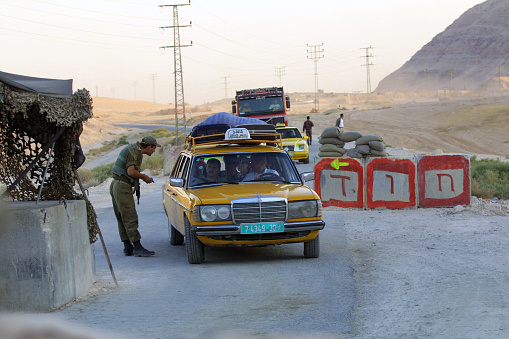 Bet Shean, Palestine - September 30, 2001: An Israel Defense Forces (IDF) soldier checks a Palestinian taxi at a checkpoint near a base in the West Bank desert in the vicinity of Jericho two days after the first anniversary of the Second Intifada. A visit by Ariel Sharon to the Temple Mount, or Noble Sanctuary, triggered the Second Intifada.