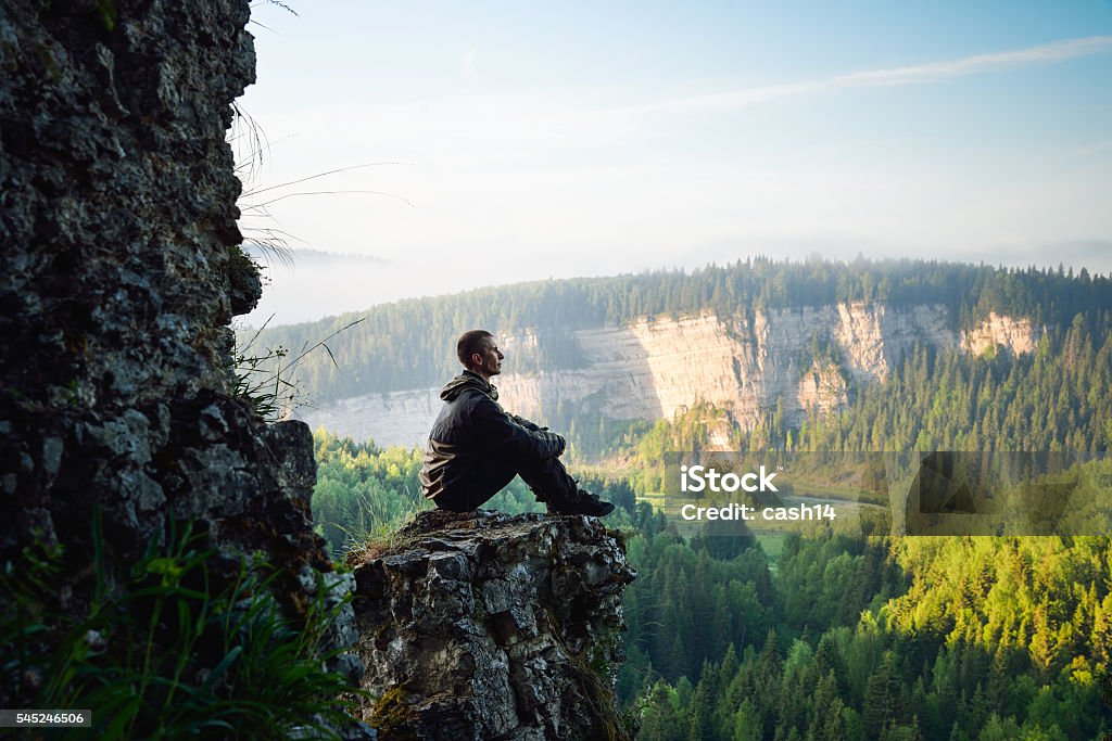 Man sitting on the top of the mountain, leisure in Man sitting on the top of the mountain, leisure in harmony with nature. Meditating Stock Photo