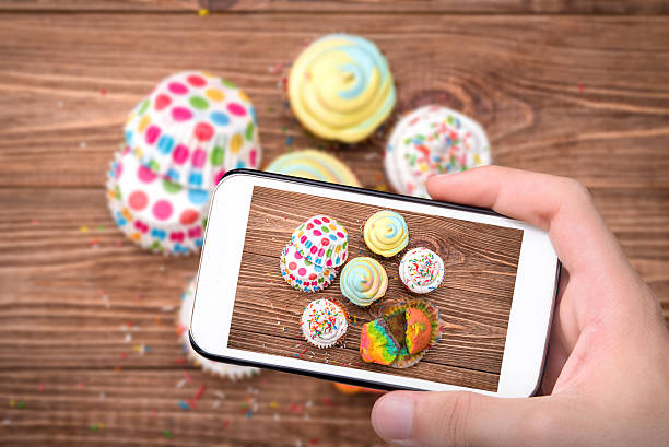 istock Hands taking photo colored cupcakes with smartphone. 545246660