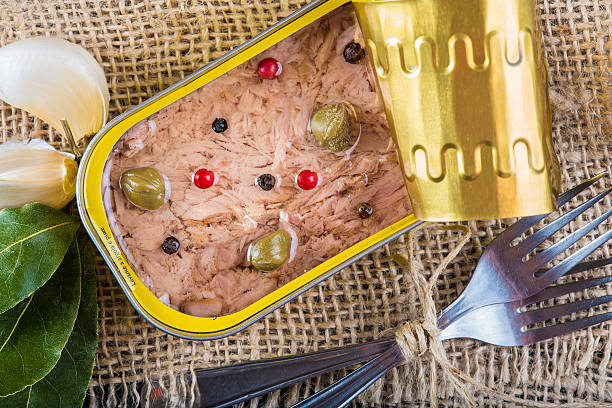Light tuna in olive oil canned Light tuna in olive oil canned dressed with herbs and spices on a burlap and a wooden background heathy snack stock pictures, royalty-free photos & images