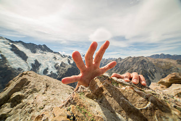 istock Human hands grabbing last rock at top of mountain peak 545254634